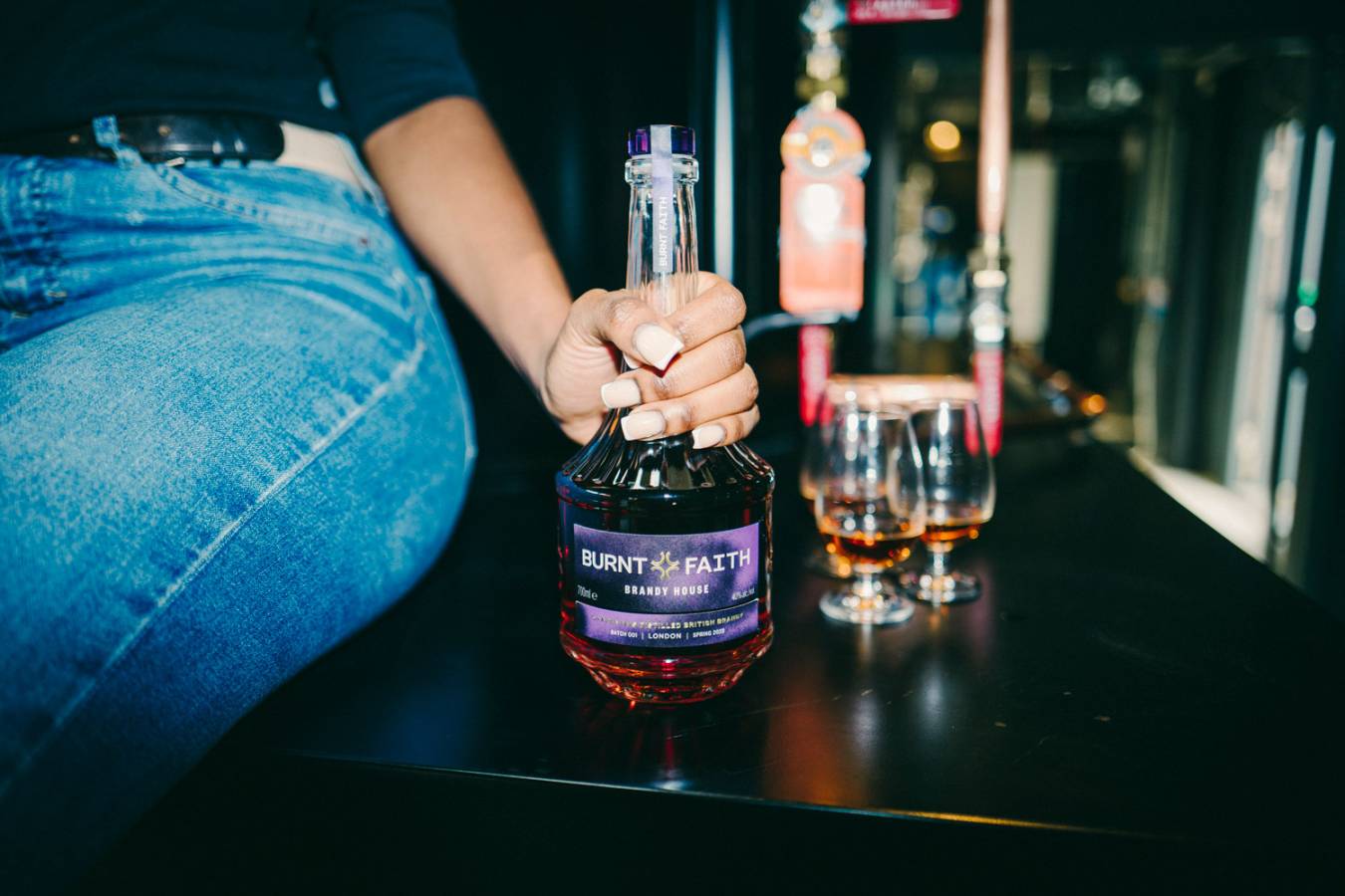 A man holding a bottle of Burnt Faith brandy