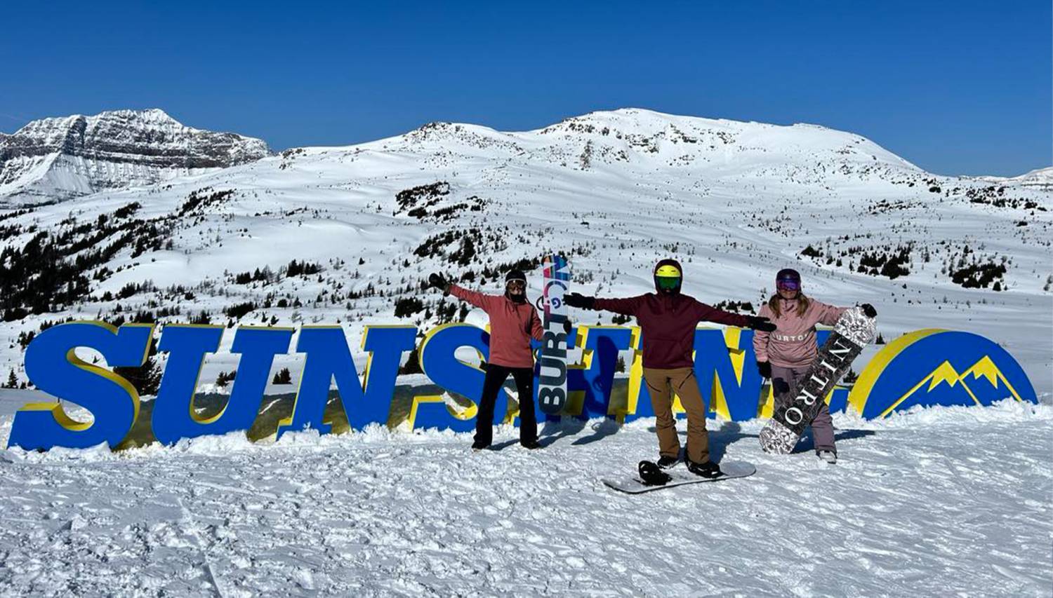 3 Women Posing In front of the Banff Sunshine Valley Ski Resort Sign on the Top Of Standish Chairlift 